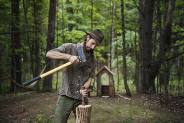 Man cutting firewood with hammer in forest - CAVF39420