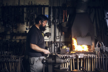 Seitenansicht eines Schmieds bei der Arbeit in der Werkstatt - CAVF39426