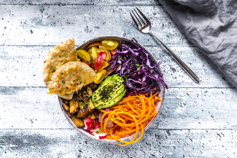 Veggie Bowl mit Tomate, Tofu, Rotkohl, Avocado, Karotte, Rötel, Kresse, schwarzem Sesam und Fladenbrot, lizenzfreies Stockfoto