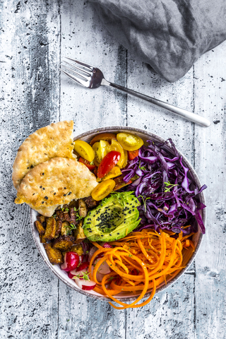 Veggie bowl with tomato, tofu, red cabbage, avocado, carrot, red redish, cress, black sesame and pita bread stock photo