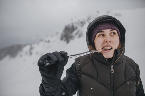 Austria, Kitzbuehel, portrait of young woman biting icicle - GUSF00629