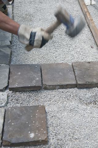 Man paving a way, cobblestones, hammering stock photo