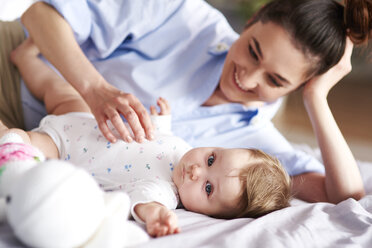 Happy mother and baby relaxing in bed at home - ABIF00302