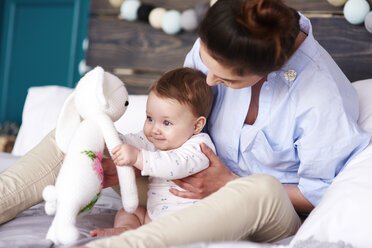 Mother and baby playing on bed at home - ABIF00304