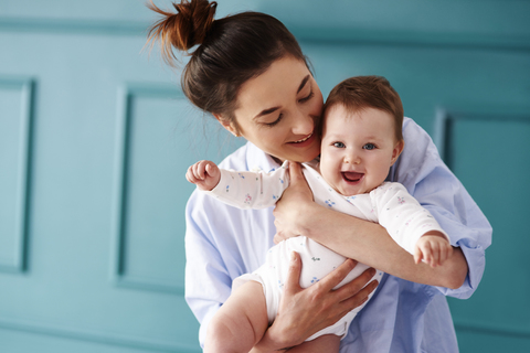 Glückliche Mutter, die ihr Baby zu Hause trägt, lizenzfreies Stockfoto