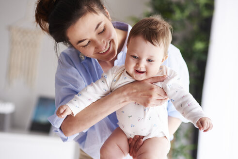 Glückliche Mutter, die ihr Baby zu Hause trägt - ABIF00311