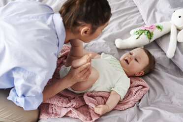 Mother and baby playing on bed at home - ABIF00316