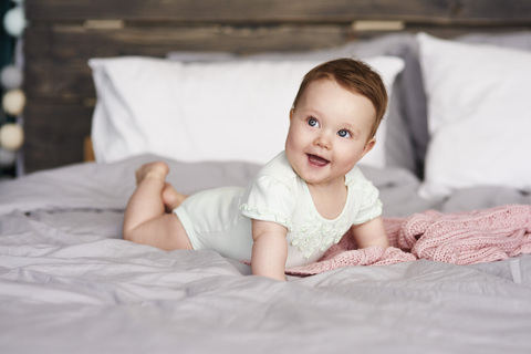 Glückliches Baby auf dem Bett liegend zu Hause, lizenzfreies Stockfoto