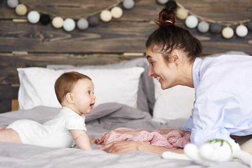 Mother and baby playing on bed at home - ABIF00319