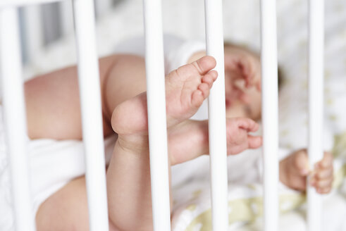 Nahaufnahme von winzigen Babyfüßen im Kinderbett - ABIF00324