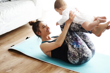 Mother and baby exercising on yoga mat at home - ABIF00336