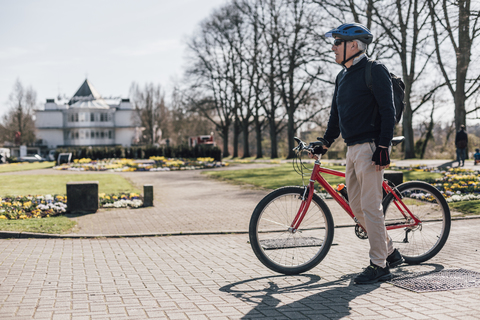 Älterer Mann mit Fahrrad in einem Park, lizenzfreies Stockfoto