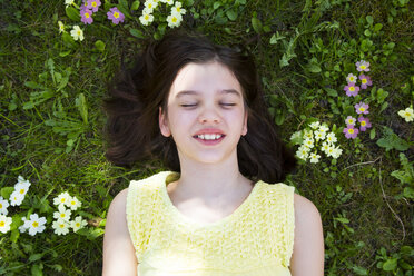 Porträt eines auf einer Blumenwiese liegenden Mädchens, Ansicht von oben - LVF06872
