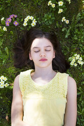 Porträt eines auf einer Blumenwiese liegenden Mädchens, Ansicht von oben - LVF06873