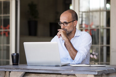 Businessman using laptop computer while sitting at table in office - CAVF39451