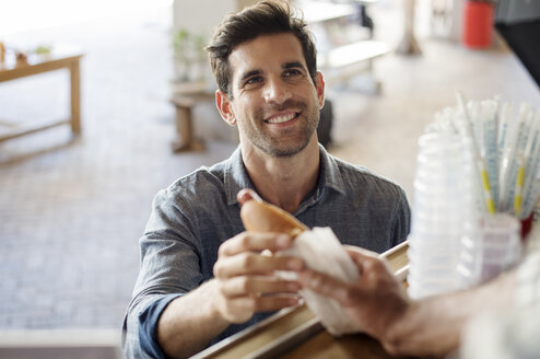 Customer receiving hotdog from male vendor at food truck - CAVF39482