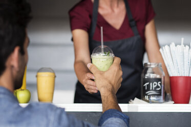 Mittelteil einer Besitzerin, die einem Kunden am Imbisswagen einen Smoothie gibt - CAVF39486