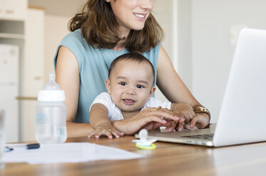 Baby boy with mother using laptop computer at home - CAVF39495