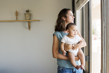 Mutter mit Baby am Fenster stehend zu Hause - CAVF39515