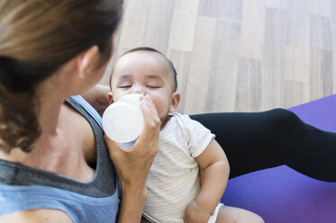 High angle view of mother feeding son while sitting at home - CAVF39533