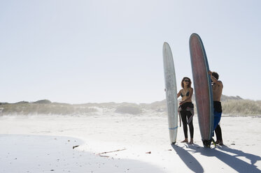 Friends with surfboards standing at beach against clear sky during sunny day - CAVF39559
