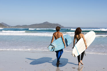 Rear view of friends carrying surfboards at beach during sunny day - CAVF39561