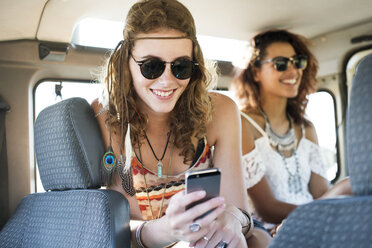 Woman using mobile phone while sitting with female friend in off-road vehicle - CAVF39572