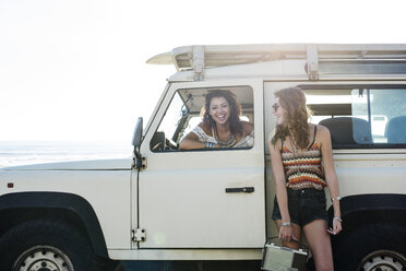 Happy woman looking at friend sitting in off-road vehicle during sunny day - CAVF39576