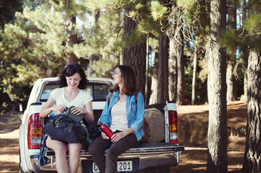 Glückliche Freundinnen, die sich auf einem Pick-up im Wald unterhalten - CAVF39616