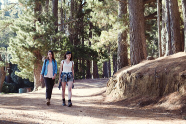 Happy female friends walking in forest - CAVF39619