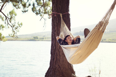 Frau schlafend in Hängematte an einem Baum am Seeufer - CAVF39623