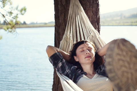 Woman sleeping on hammock at lakeshore stock photo