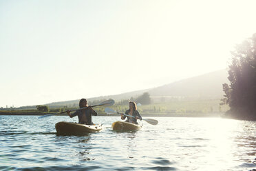 Cheerful female friends kayaking on lake clear sky during sunny day - CAVF39635