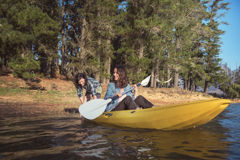 Glückliche Freundinnen mit Kajak auf dem See, lizenzfreies Stockfoto