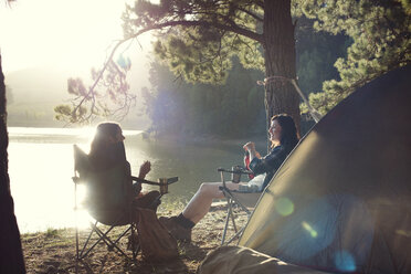 Freundinnen entspannen sich auf einem Campingplatz am See bei strahlendem Sonnenschein - CAVF39639