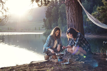 Freundinnen machen Essen am See auf dem Campingplatz - CAVF39647