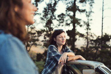 Female friends by convertible car looking away - CAVF39650