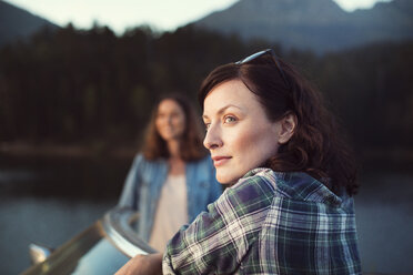 Female friends looking away while standing by convertible car - CAVF39651