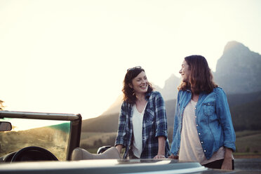 Female friends talking while standing by convertible car against clear sky - CAVF39654