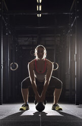 Full length of determined female athlete lifting kettle bell in gym - CAVF39684