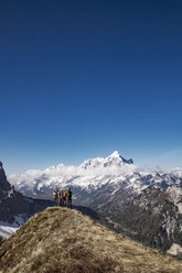 Hikers standing on mountain against clear blue sky - CAVF39697