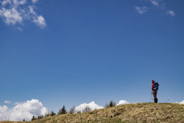 Niedriger Blickwinkel von weiblichen Wanderer stehen auf Berg gegen blauen Himmel - CAVF39698