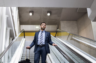 Geschäftsmann mit Gepäck auf einer Rolltreppe in einer U-Bahn-Station stehend - CAVF39703
