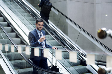 Geschäftsmann benutzt Smartphone auf Rolltreppe in U-Bahn-Station - CAVF39711