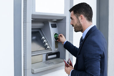 Seitenansicht eines Geschäftsmannes, der einen Geldautomaten in einer U-Bahn-Station benutzt - CAVF39714