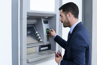 Side view of businessman using ATM at subway station - CAVF39714