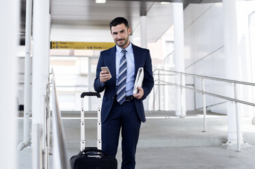 Portrait of confident businessman holding smart phone at subway station - CAVF39716