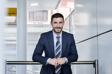 Portrait of confident businessman leaning on railing at subway station - CAVF39718