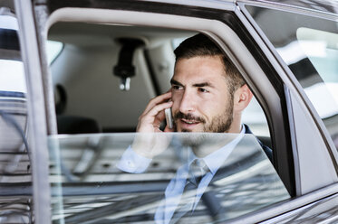 Businessman looking away while using smart phone in car - CAVF39722