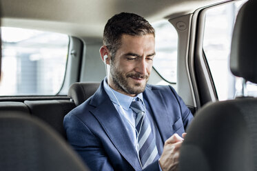 Businessman listening music through earphones in car - CAVF39724